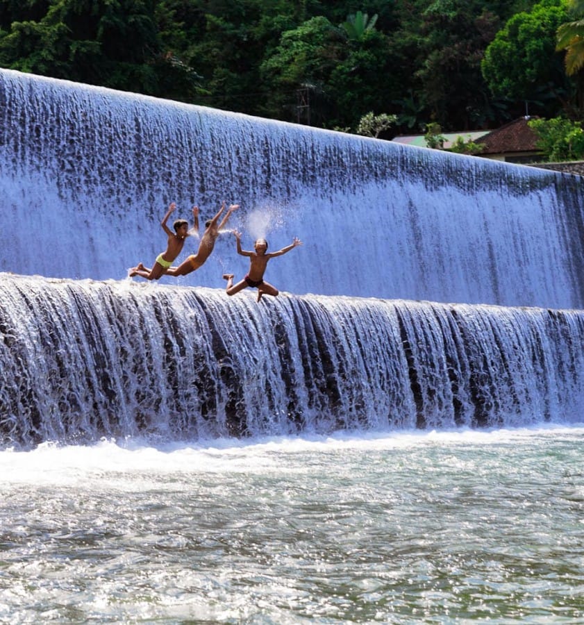 Tampak anak-anak terjun ke sungai dengan menyemburkan air dari mulut mereka