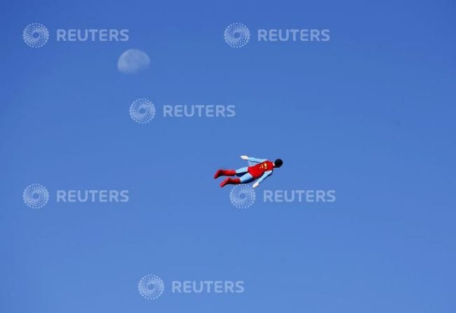 A radio-controlled Superman plane, flown by designer Otto Dieffenbach, passes the moon during a test flight in San Diego