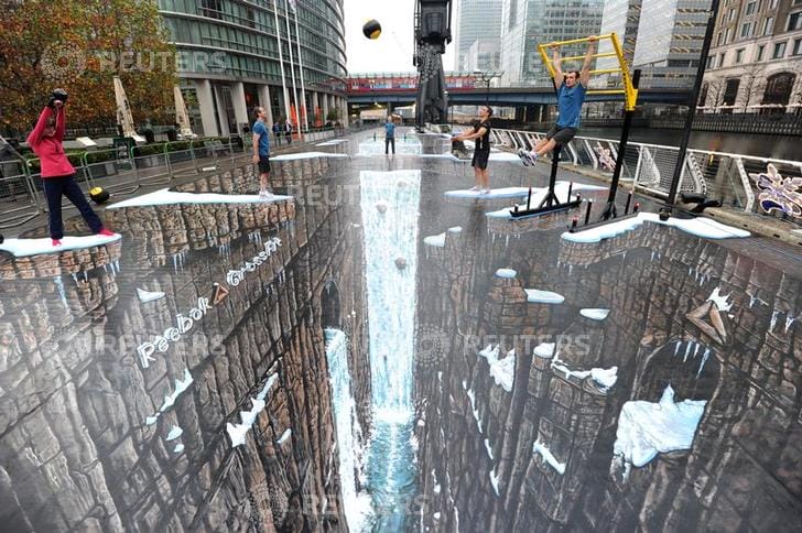 Actors pose with gym equipment on what the Guinness World Records bills as the world's largest 3D painting, at Canary Wharf in London