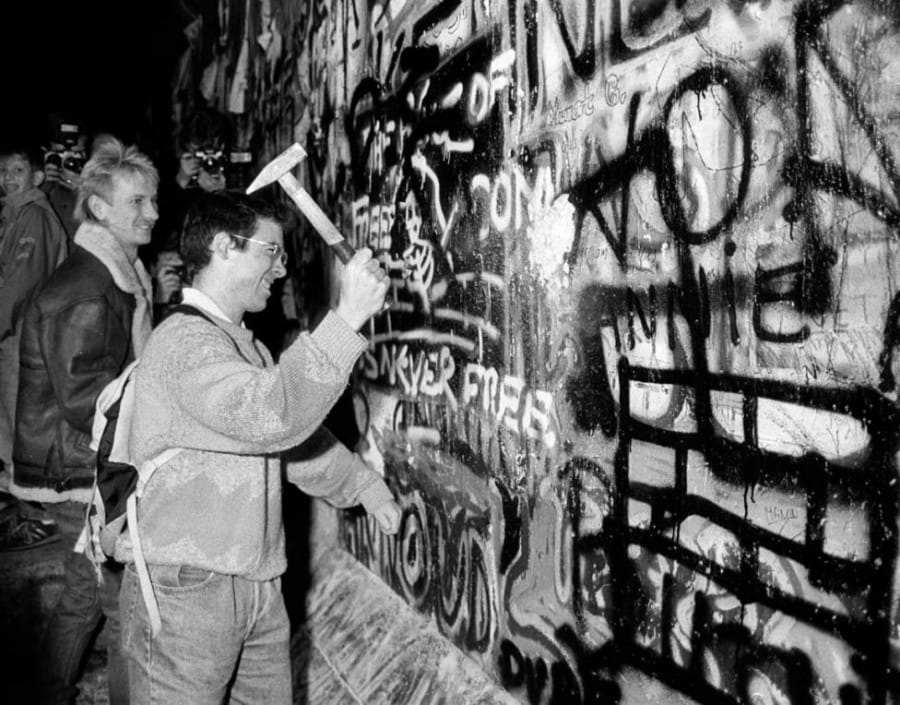 Seorang Warga sedang Menghancurkan Tembok Berlin dengan Palu