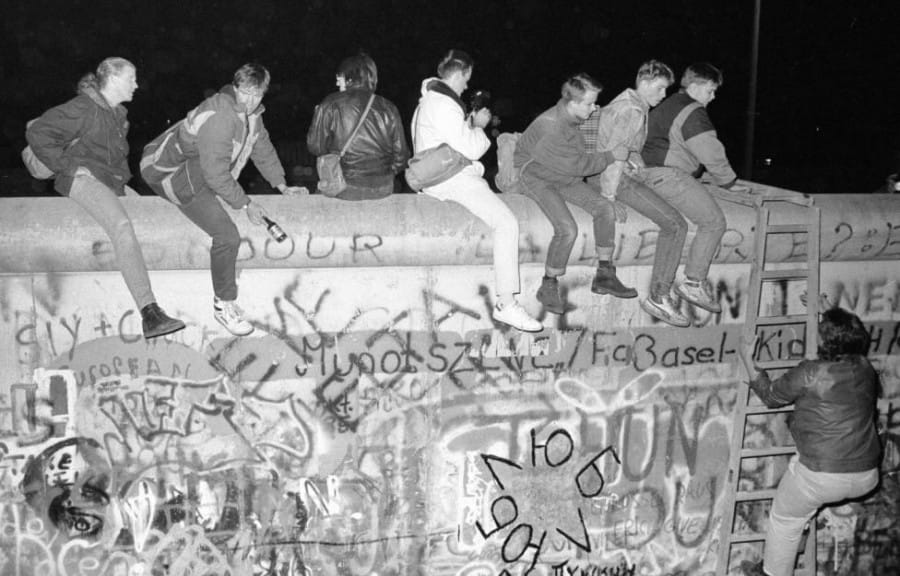 Warga Jerman Timur sedang Duduk di Atas Tembok Berlin
